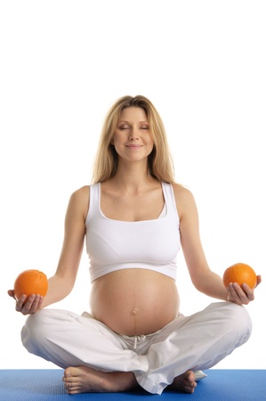 Pregnant woman practicing yoga with orangesの写真素材