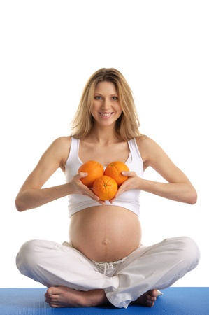 Pregnant woman practicing yoga with orangesの写真素材