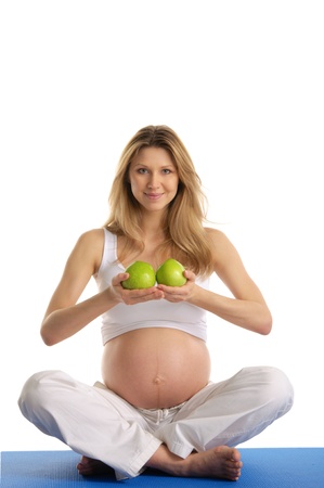Pregnant woman practicing yoga and keeps applesの写真素材