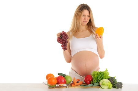 Unhappy pregnant woman with fruits and vegetables isolated on whiteの写真素材