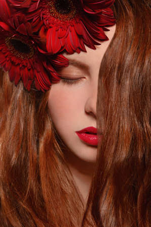 Redhead girl with red gerbera in teethの写真素材