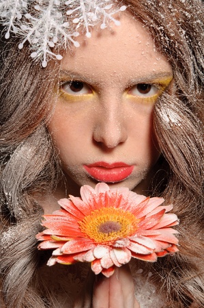 girl with flower in his hand under falling snowの写真素材