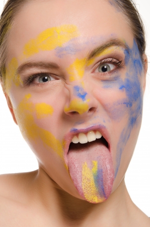 woman with paint on his face shows tongueの写真素材