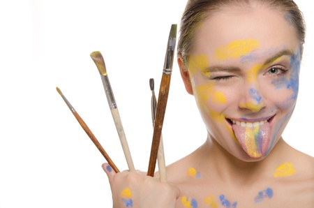 woman with brushes and  paint on face shows tongueの写真素材