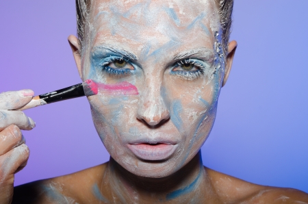 Woman paints her face with different colorsの写真素材