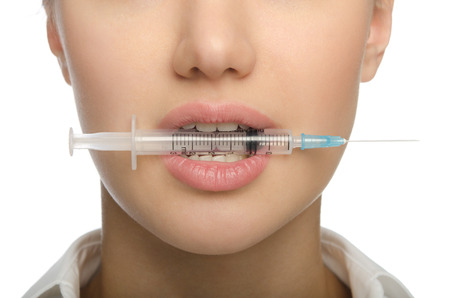 Girl biting a syringe with a needleの写真素材