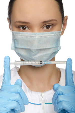 Young nurse in mask holding syringe isolated on whiteの写真素材