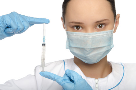 Young nurse in mask and gloves holding a syringe isolated on whiteの写真素材