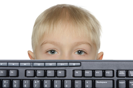 Little boy looks out keyboard isolated on whiteの写真素材
