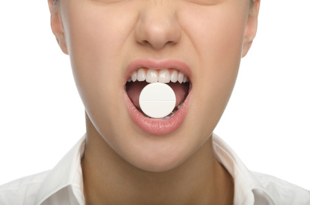 Big tablet in the teeth of women isolated in whiteの写真素材