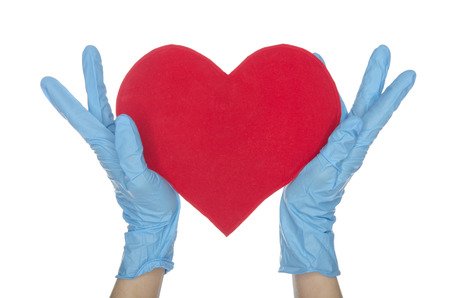 Hands in blue medical gloves keep heart on white の写真素材