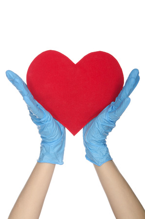 Two hands in medical gloves keep heart on white の写真素材