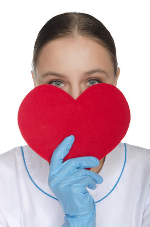 Doctor peeking out from behind a red heart symbolの写真素材