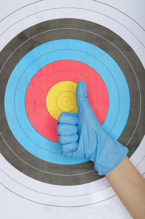 Hand in glove on background of multicolored targetの写真素材