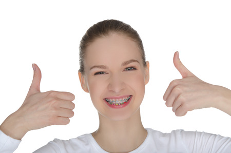 Smiling happy girl with braces isolated on whiteの写真素材