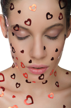 Woman with closed eyes and hearts on the face isolated on whiteの写真素材