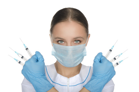 Doctor in mask and gloves holding syringe in his hands front of faceの写真素材