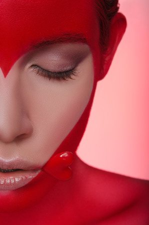 Half portrait of young woman with picture and heart on face and mouthの写真素材