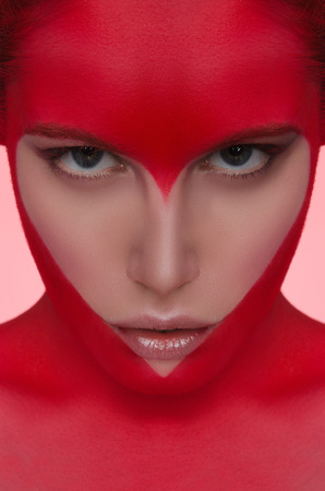 Female face with red face art in the form of heartの写真素材