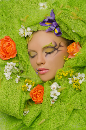 Vertical portrait of beautiful woman in flowers on green の写真素材