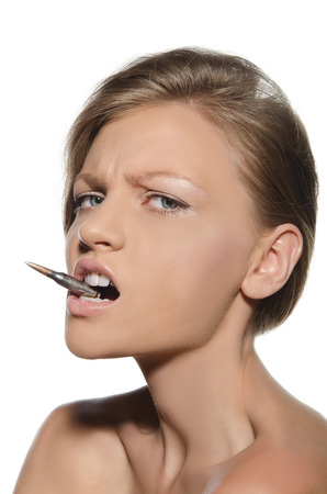 Portrait of young woman with bullet in mouth isolated on whiteの写真素材