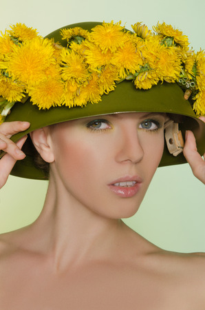 Young woman in helmet with a wreath of yellow dandelionsの写真素材