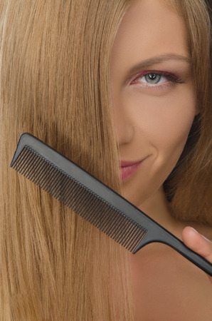beautiful young woman holding comb straightened hairの写真素材