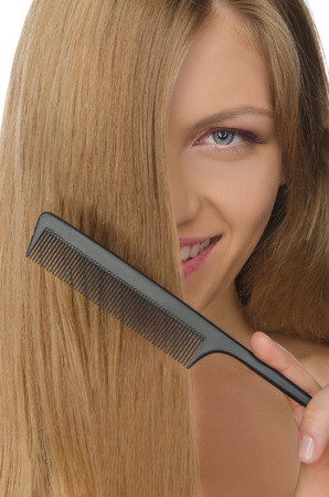 beautiful young woman holding comb straightened hairの写真素材
