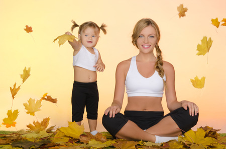 young beautiful woman and child do yoga under leavesの写真素材