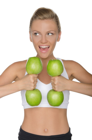 Young woman with dumbbells from ripe apples looking away isolated on whiteの写真素材