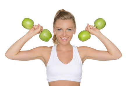 Young woman with dumbbells from ripe apples isolated on whiteの写真素材