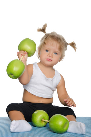 Little girl with weights of green apples isolated on whiteの写真素材