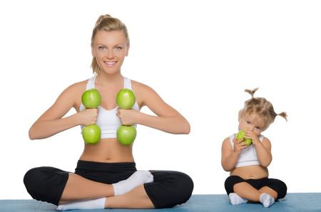 Mom and daughter engage in fitness dumbbells of green applesの写真素材