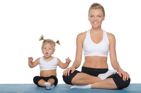 Happy mom and daughter engage in fitness on blue matの写真素材