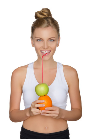 attractive woman drinking juice from apple and orange isolated on whiteの写真素材