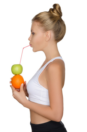 Beautiful woman drinking juice from fruits isolated on whiteの写真素材