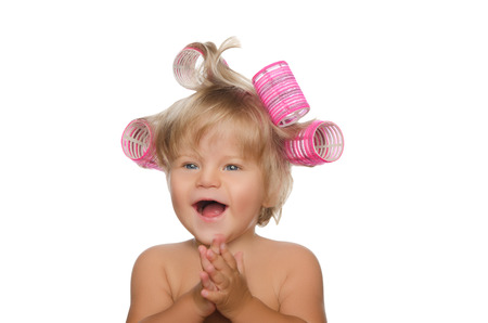 little laughing girl with hair curlers isolated on whiteの写真素材