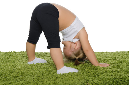 Little girl doing stretching exercises on green carpetの写真素材
