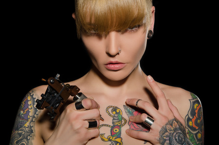 beautiful blonde with tattoo machine and for them, dark backgroundの写真素材