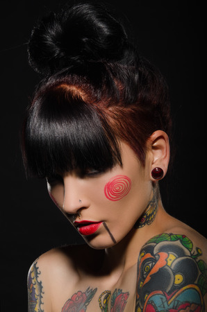 Young brunette with a tattoo on body, dark backgroundの写真素材