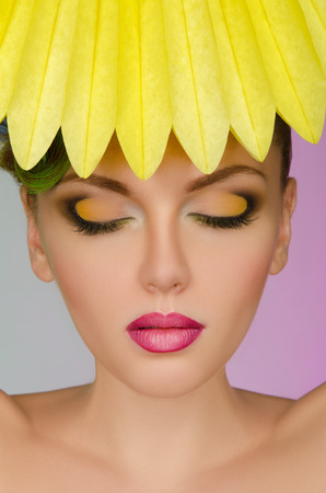 Beautiful woman with yellow paper on colorful backgroundの写真素材