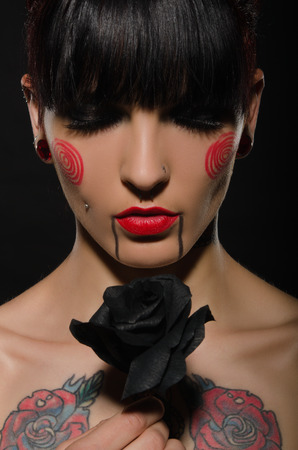 tattooed brunette with black flower on dark backgroundの写真素材
