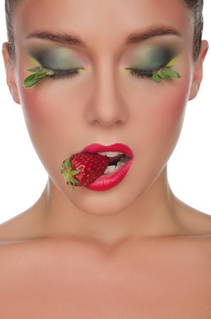 face of young woman with strawberry in mouth isolated on whiteの写真素材