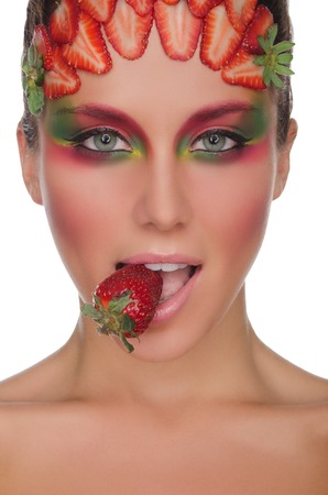 Beautiful woman with strawberries on face and teeth isolated on whiteの写真素材