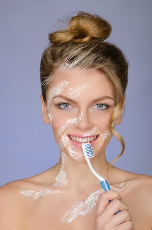 smiling woman with toothbrush and toothpaste on a blue backgroundの写真素材