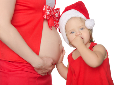 child listening to belly of pregnant woman at Christmas isolated on whiteの写真素材