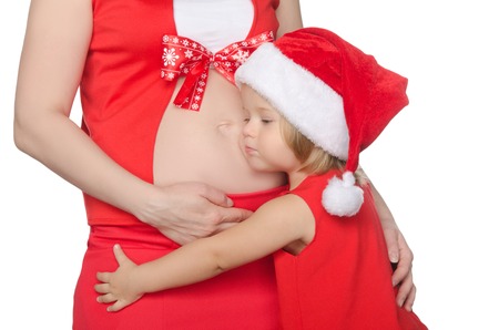 child hugs belly of pregnant woman at Christmas isolated on whiteの写真素材