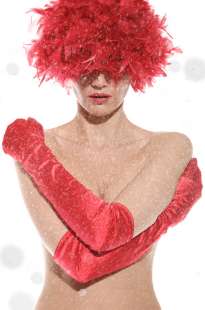 sexy woman in red wig, gloves covers breast, with snow isolated on whiteの写真素材