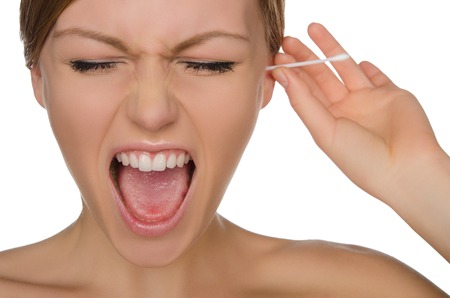 woman screams and cleans ears with cotton sticks isolated on whiteの写真素材