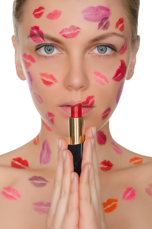 Beautiful woman with kisses on face holding lipstick isolated on whiteの写真素材